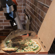 Robotic arm slices finished pizza in box